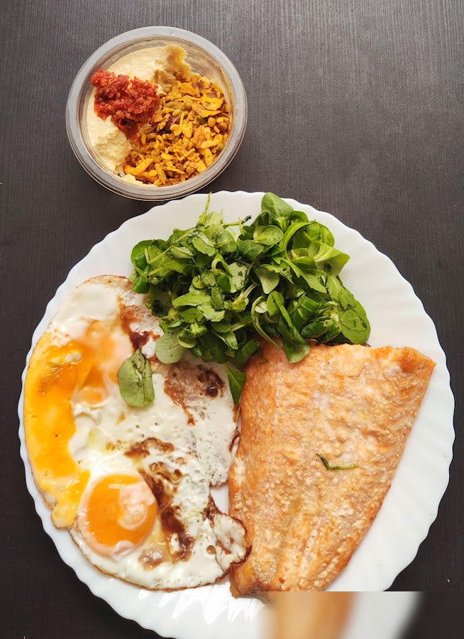 Salmon with fried eggs and greens