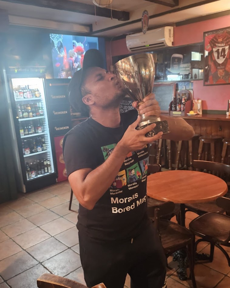 Jimmy Humania kissing a silver trophy in Moralis Bored Mage shirt